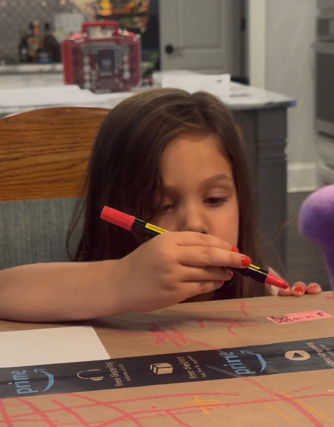 Ellie, age four, drawing X marks on a cardboard box with a marker.